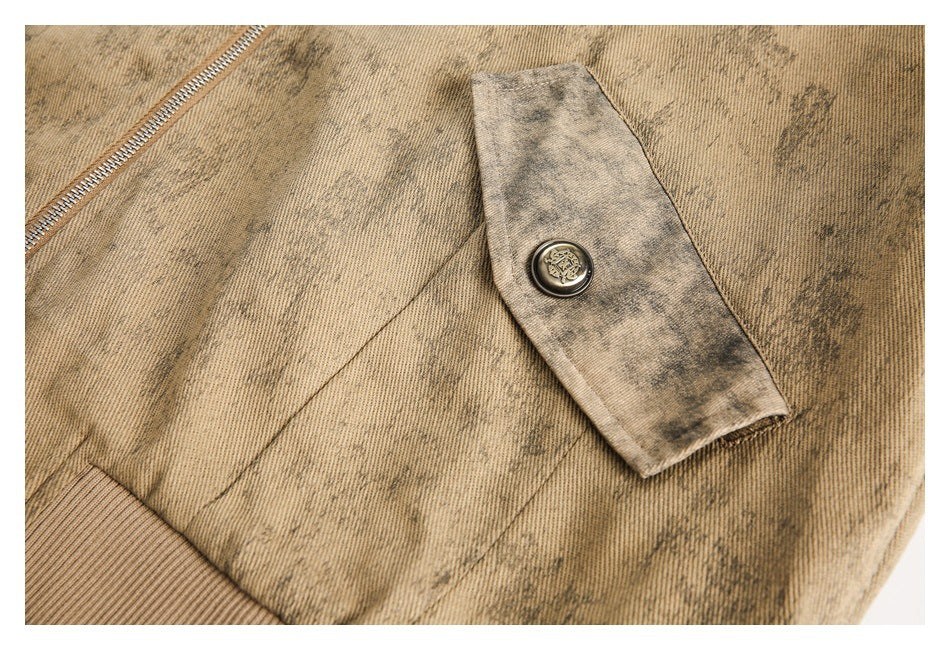 Close-up of a buttoned fabric tab on the tan mottled jacket, with a ribbed cuff and zipper edge visible.