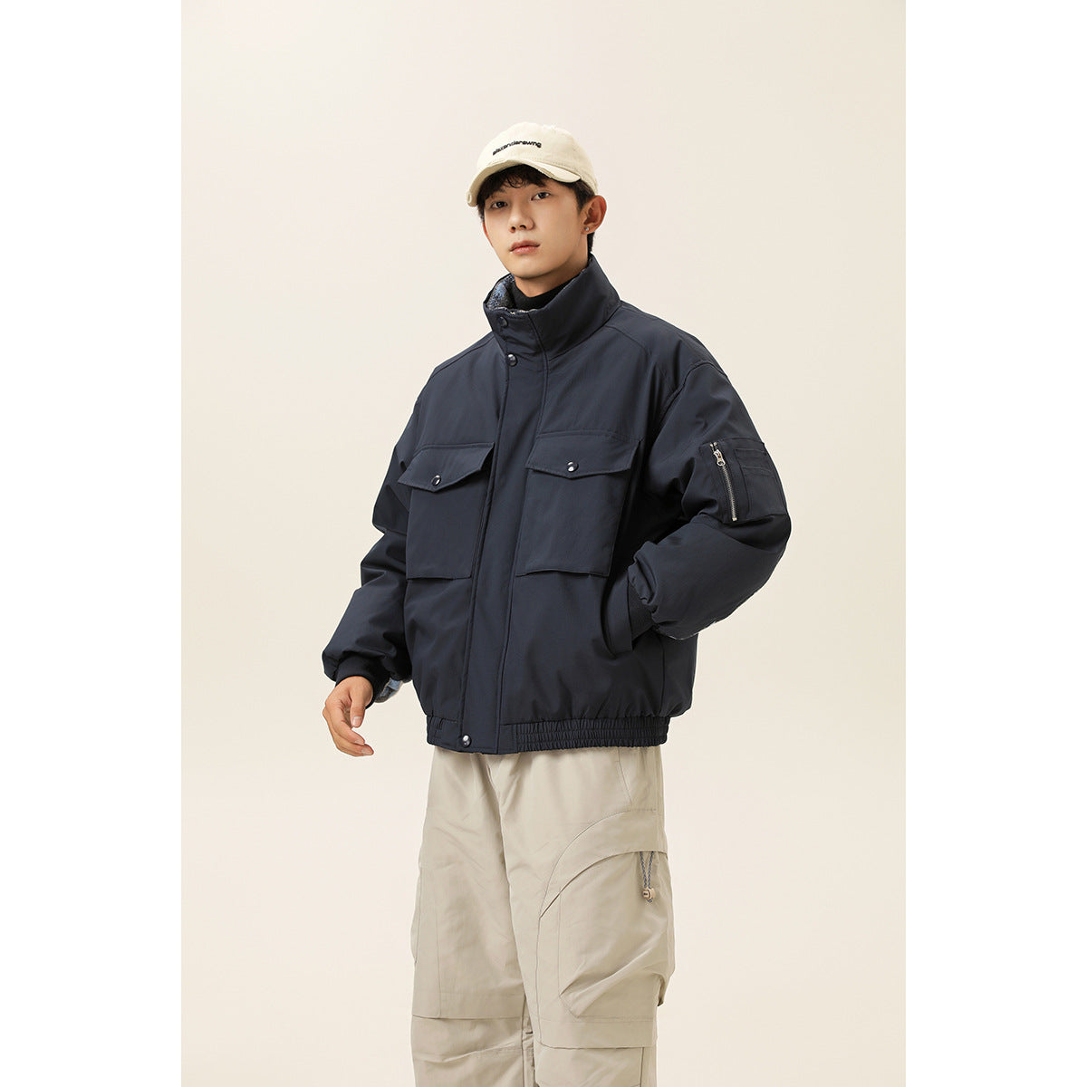 Model wearing a dark navy jacket with a stand collar, flap chest pockets, and a zippered sleeve pocket.