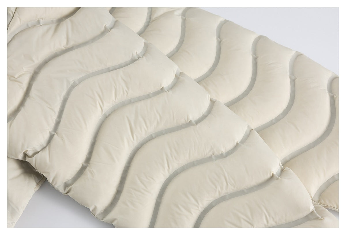 Close-up of ivory padded fabric with broad curved channels outlined in gray piping.
