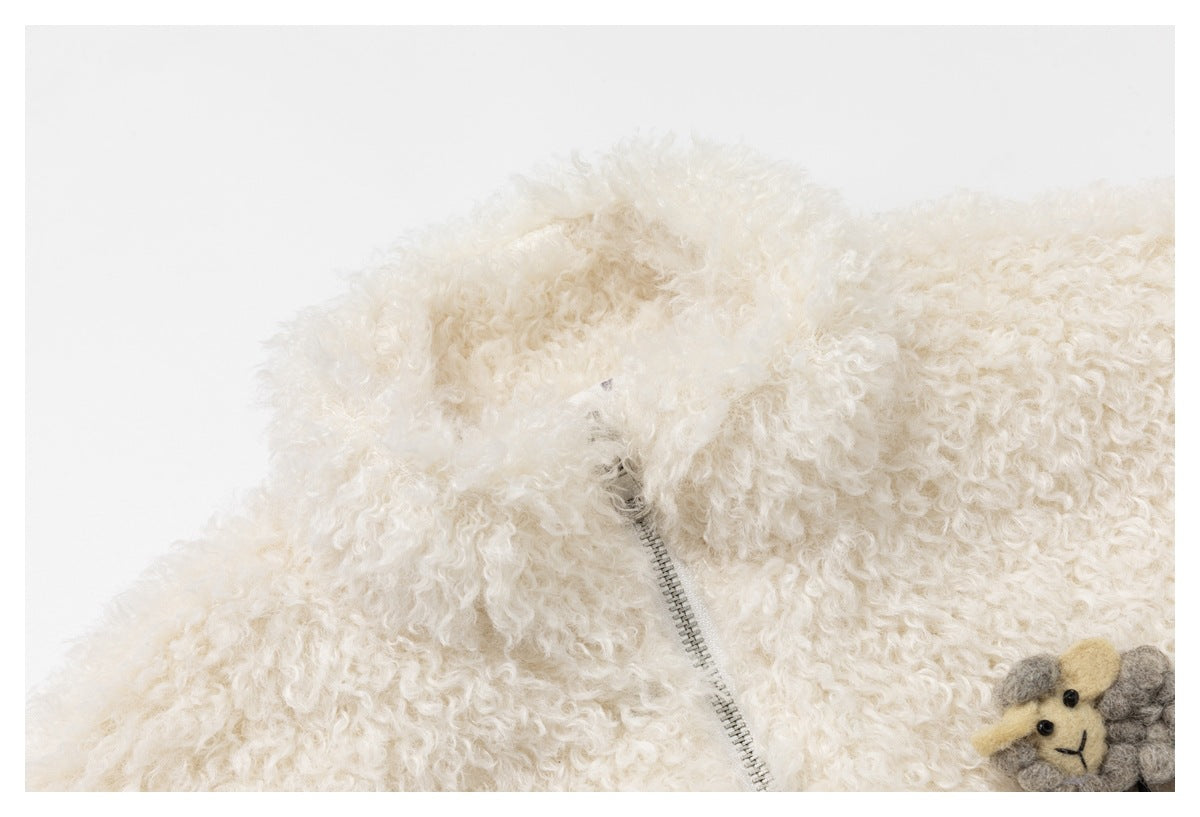 Close-up of a cream curly-pile garment with a metal zipper and part of a sheep appliqué.