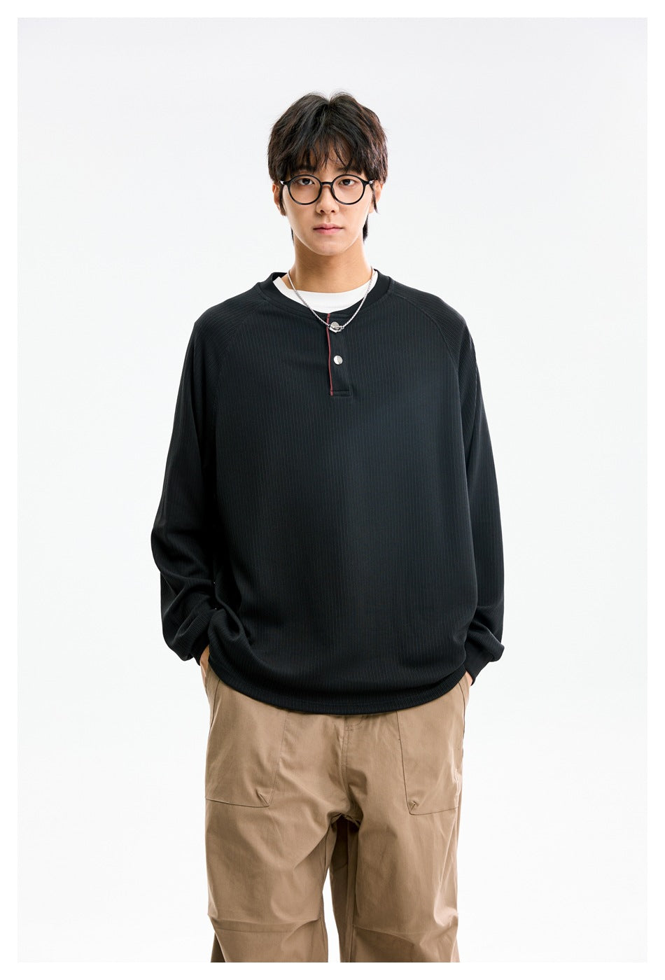 Model wearing a black ribbed long-sleeve henley with a short button placket and thin red trim.