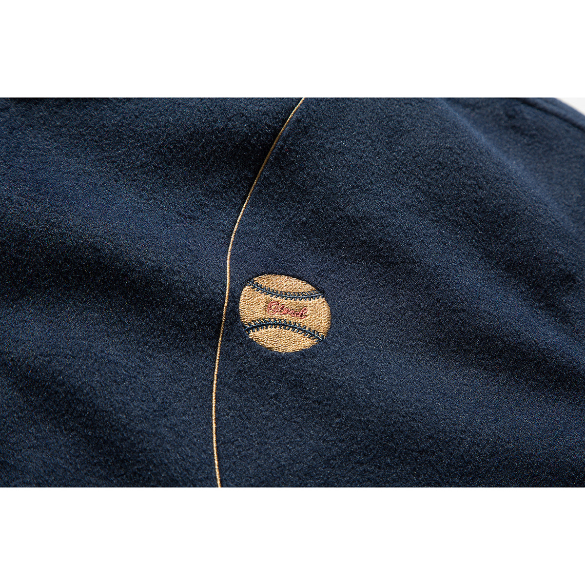 Close-up of a small embroidered emblem and contrast piping on dark navy jacket fabric.