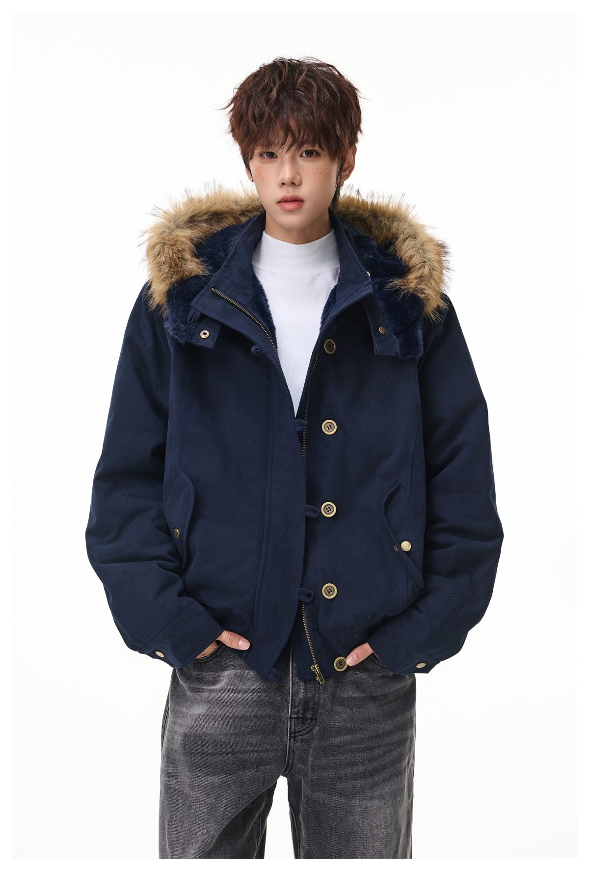 Person wearing a navy hooded jacket with faux-fur trim and plush lining, open front over a white top, with gray jeans
