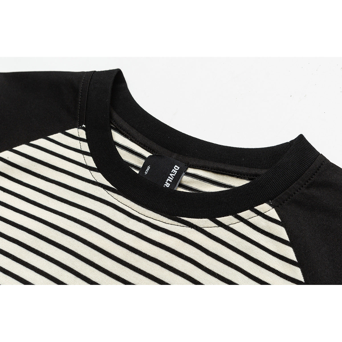 Close-up of a black ribbed crew neckline and cream-and-black striped shirt front.