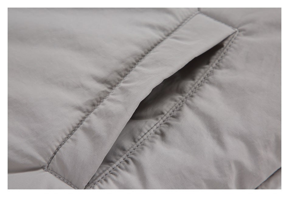 Close-up of a slanted welt pocket opening and stitching on the light gray jacket.