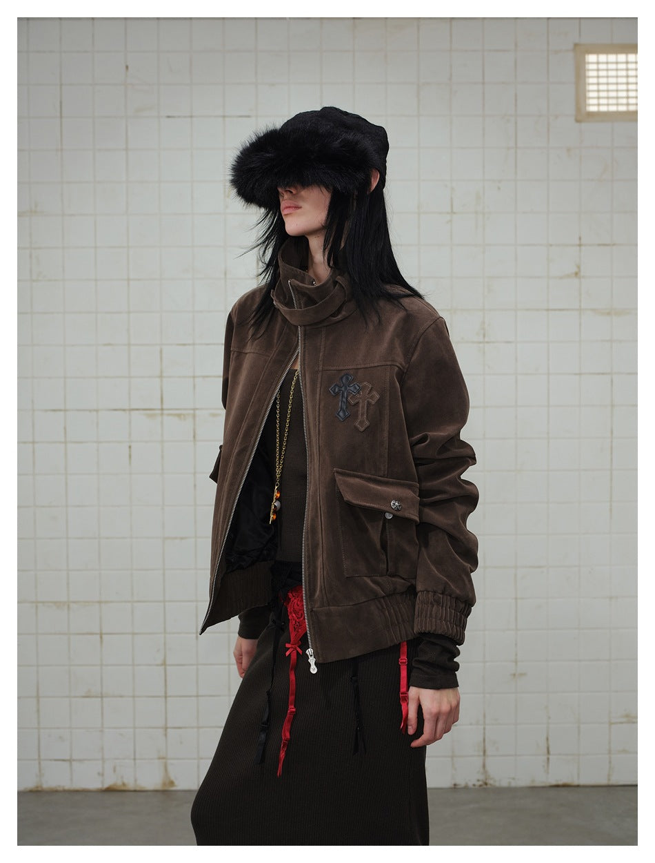 Three-quarter view of a model wearing a dark brown high-collar jacket with a front zipper, flap pockets and chest appliqué.