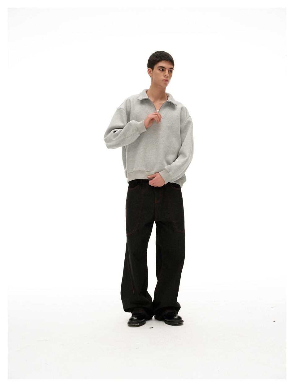 Model wearing a light gray quarter-zip pullover with black wide-leg pants and black shoes, adjusting the neckline.