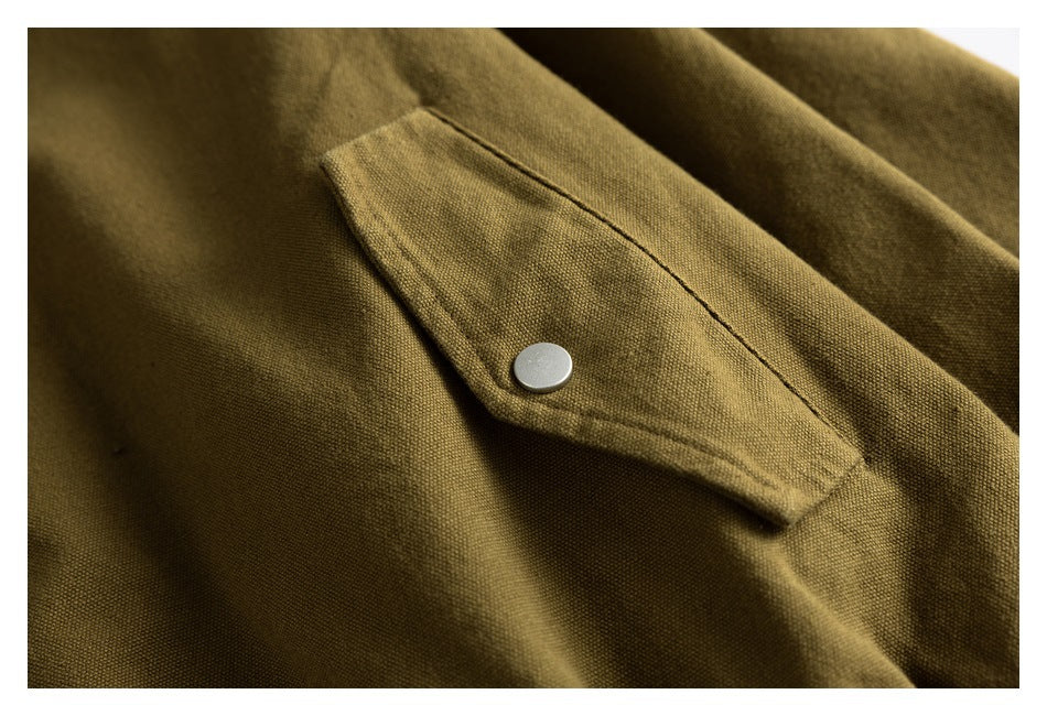Close-up of an olive-brown jacket flap pocket with a round silver snap button.