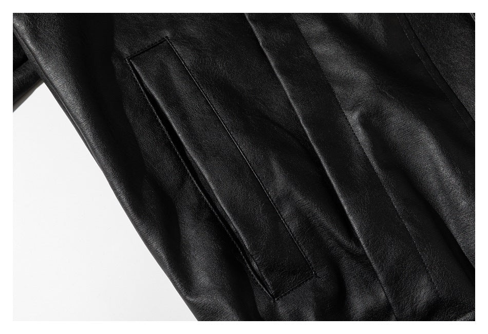 Close-up of a black leather-look garment with a slanted welt pocket and stitched panel seams.
