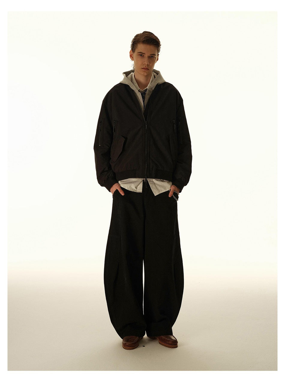 Front view of a model wearing a black bomber jacket with zip pockets, layered over a gray hoodie and shirt.
