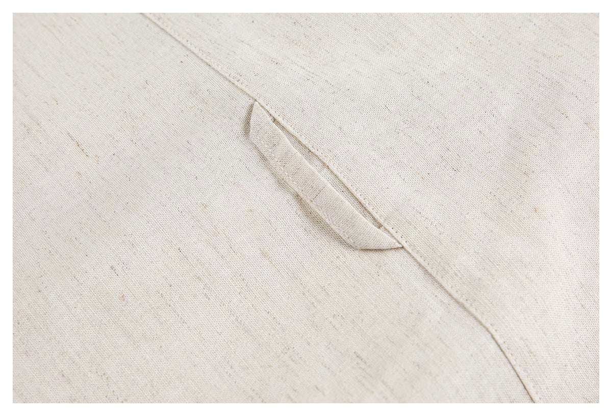 Close-up of a narrow fabric loop or tab beside a seam on an ivory flecked garment.