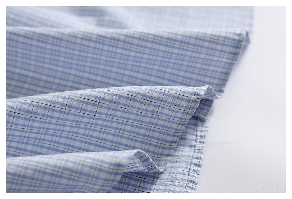 Close-up of light blue and white checkered fabric with fine dark grid lines, folded against a white background.