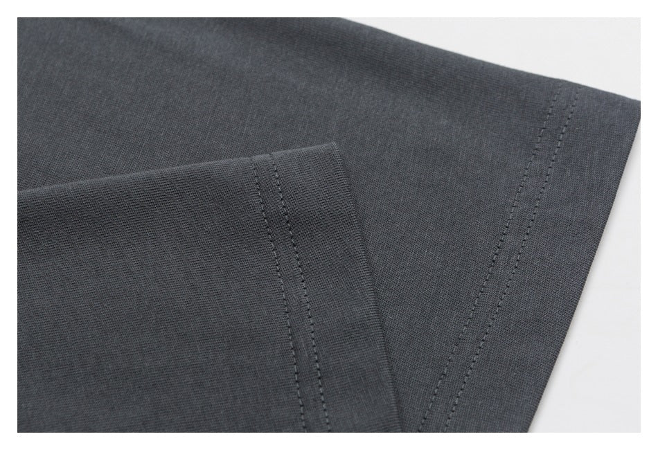 Close-up of dark charcoal fabric with overlapping stitched seams.