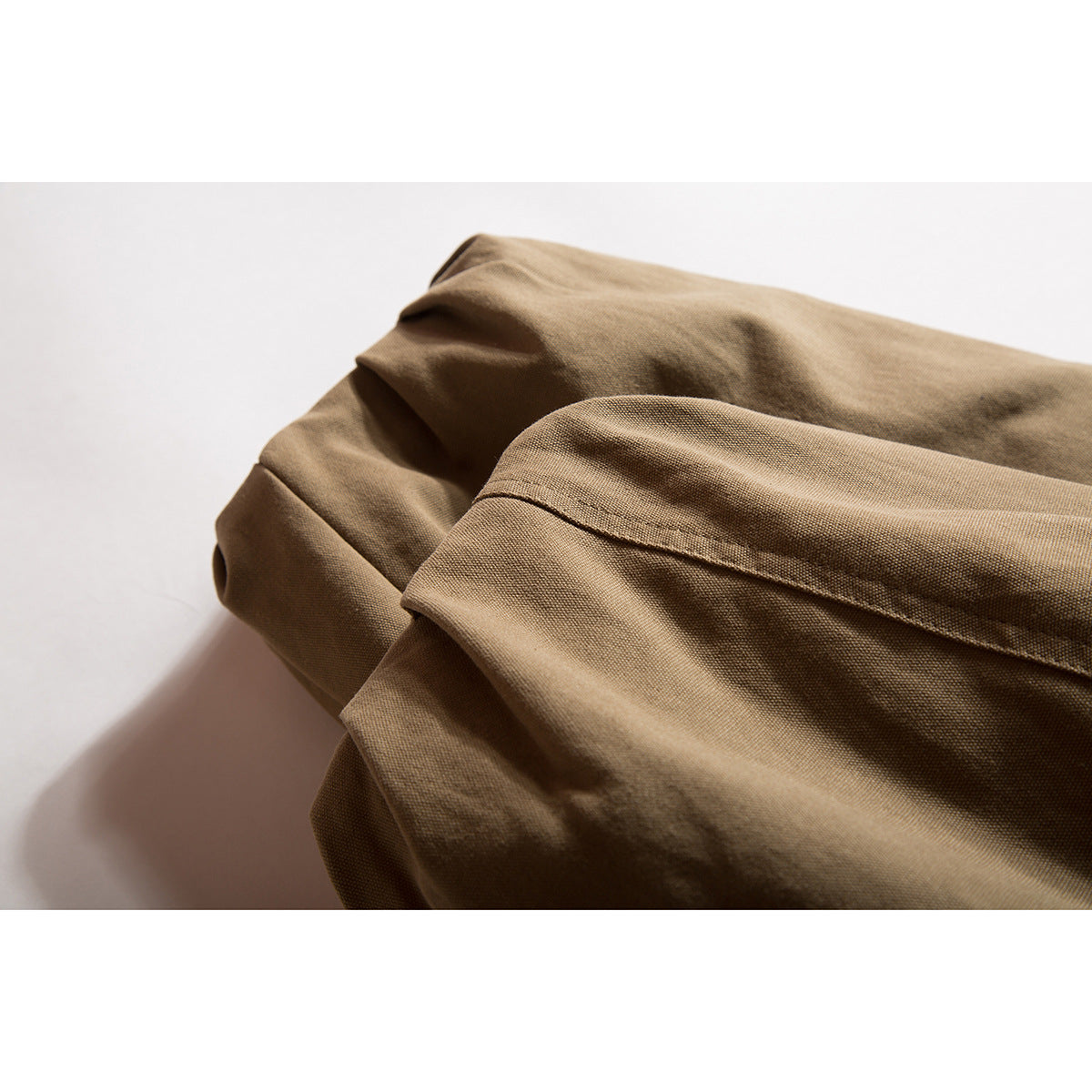Close-up of folded brown jacket fabric and a stitched seam.