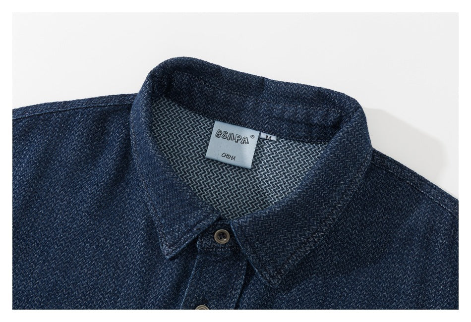 Close-up of a dark blue patterned shirt collar, buttons, and neck label.