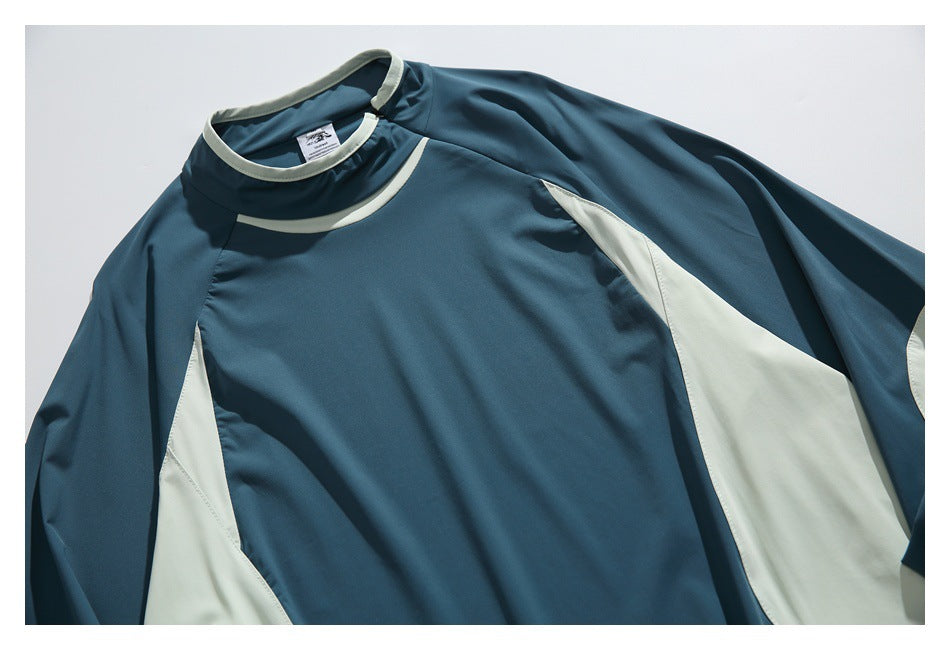 Angled close view of the front of a teal pullover with a high collar, pale trim, and pale side panels.