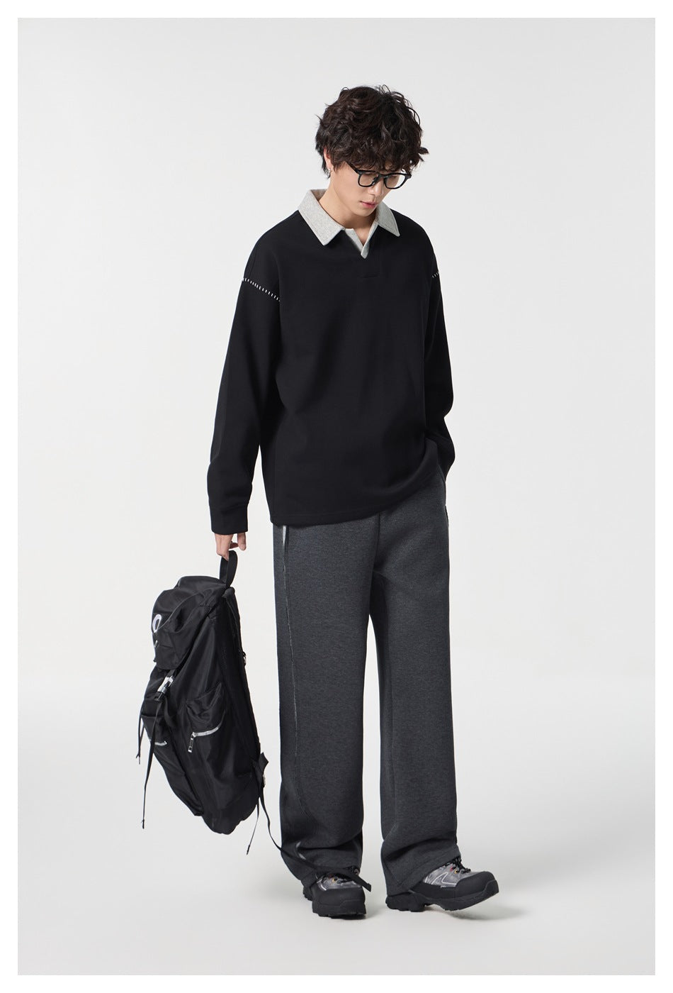 Model wearing a black long-sleeve pullover with a light gray collar and stitched shoulder details.
