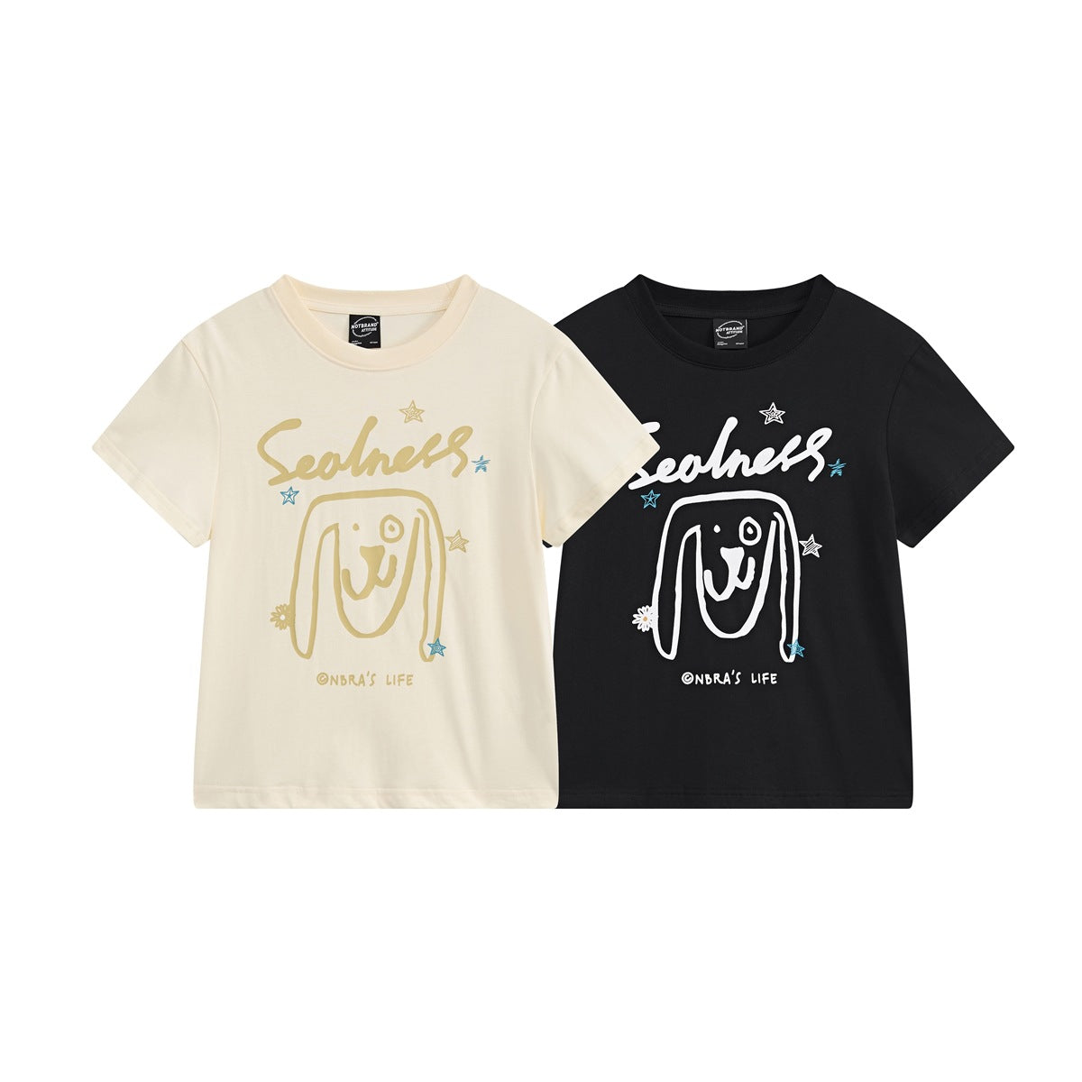 Front view of cream and black short-sleeve T-shirts with playful face, star, and lettering graphics.