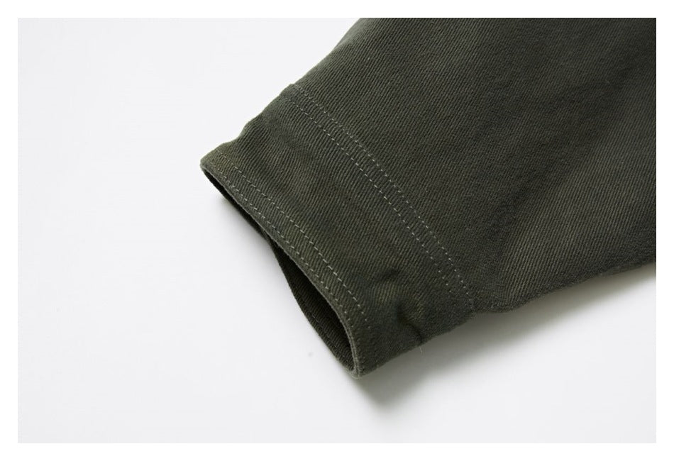 Close-up of a dark olive garment cuff showing the folded edge and parallel rows of stitching.