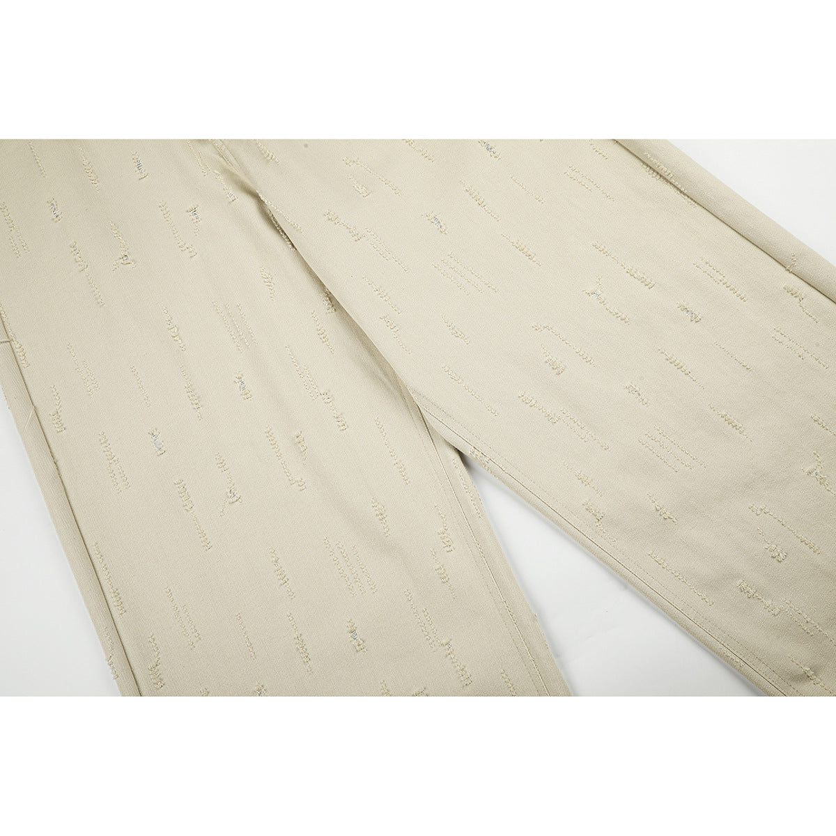 Close-up of the wide trouser legs, showing scattered linear details on light beige fabric.