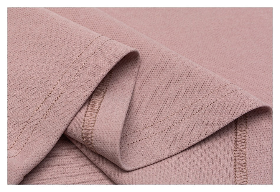 Close-up of folded dusty rose shirt hems showing stitching and overlocked inner seams.