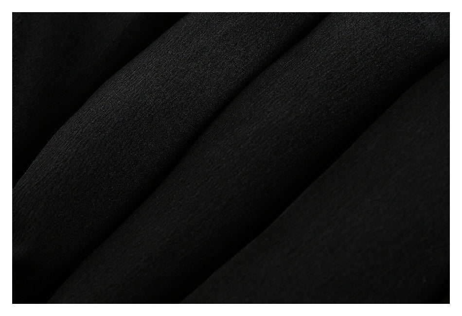 Close-up of black garment fabric showing a subtle woven texture and soft folds.