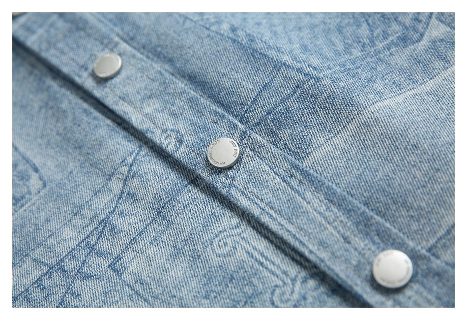 Close-up of a blue printed denim placket with three round silver buttons.
