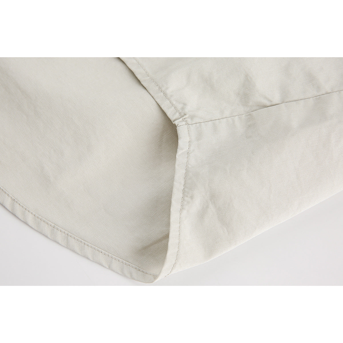 Close-up of stitching and a curved seam on a light-colored shirt.