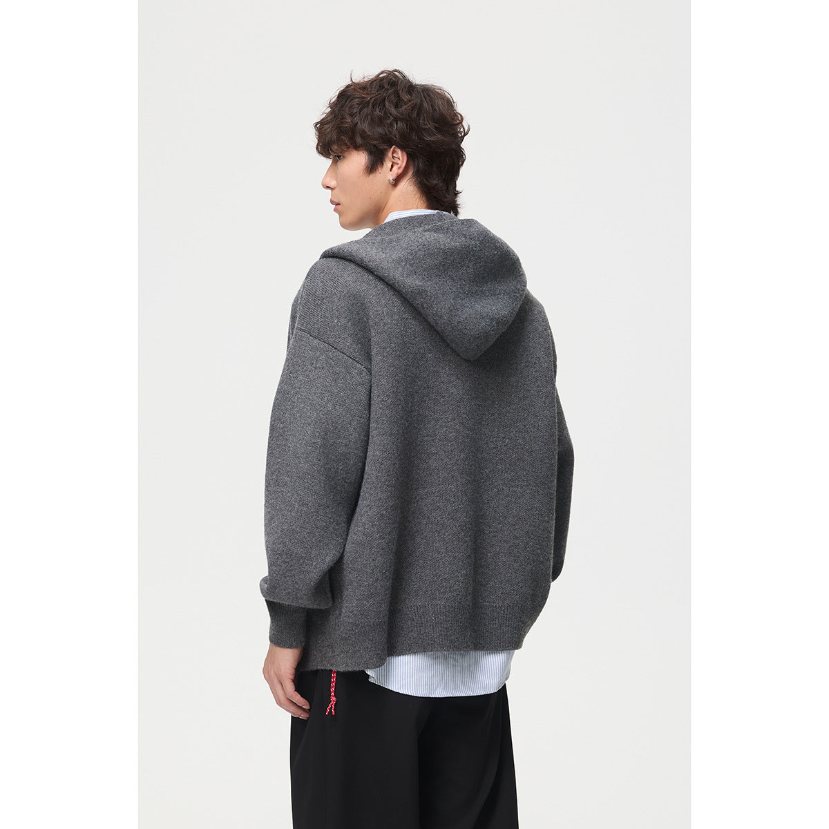 Rear view of a model wearing a charcoal-gray hooded knit cardigan over a striped shirt.