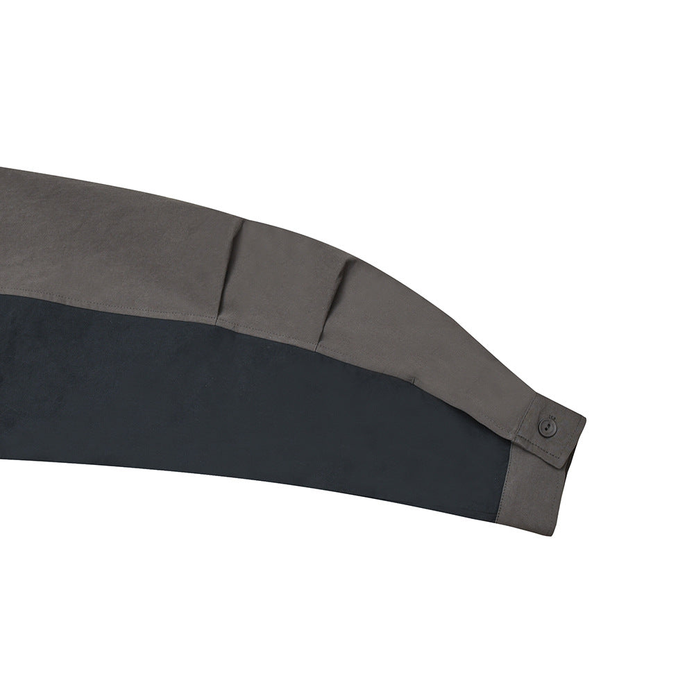 Close-up of a gray jacket sleeve with a wide navy panel and a buttoned cuff tab.