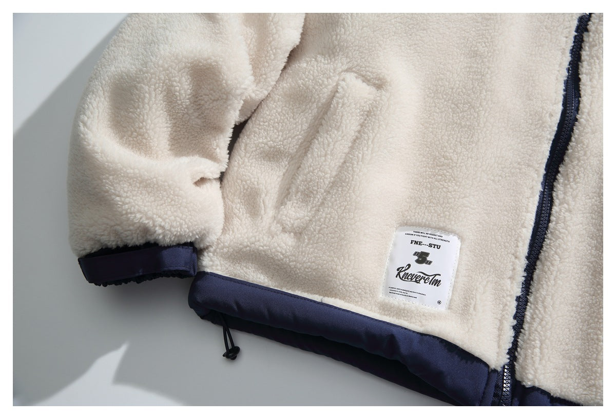Close-up of a cream sherpa jacket showing its sleeve, dark navy trim, zipper, and sewn label.