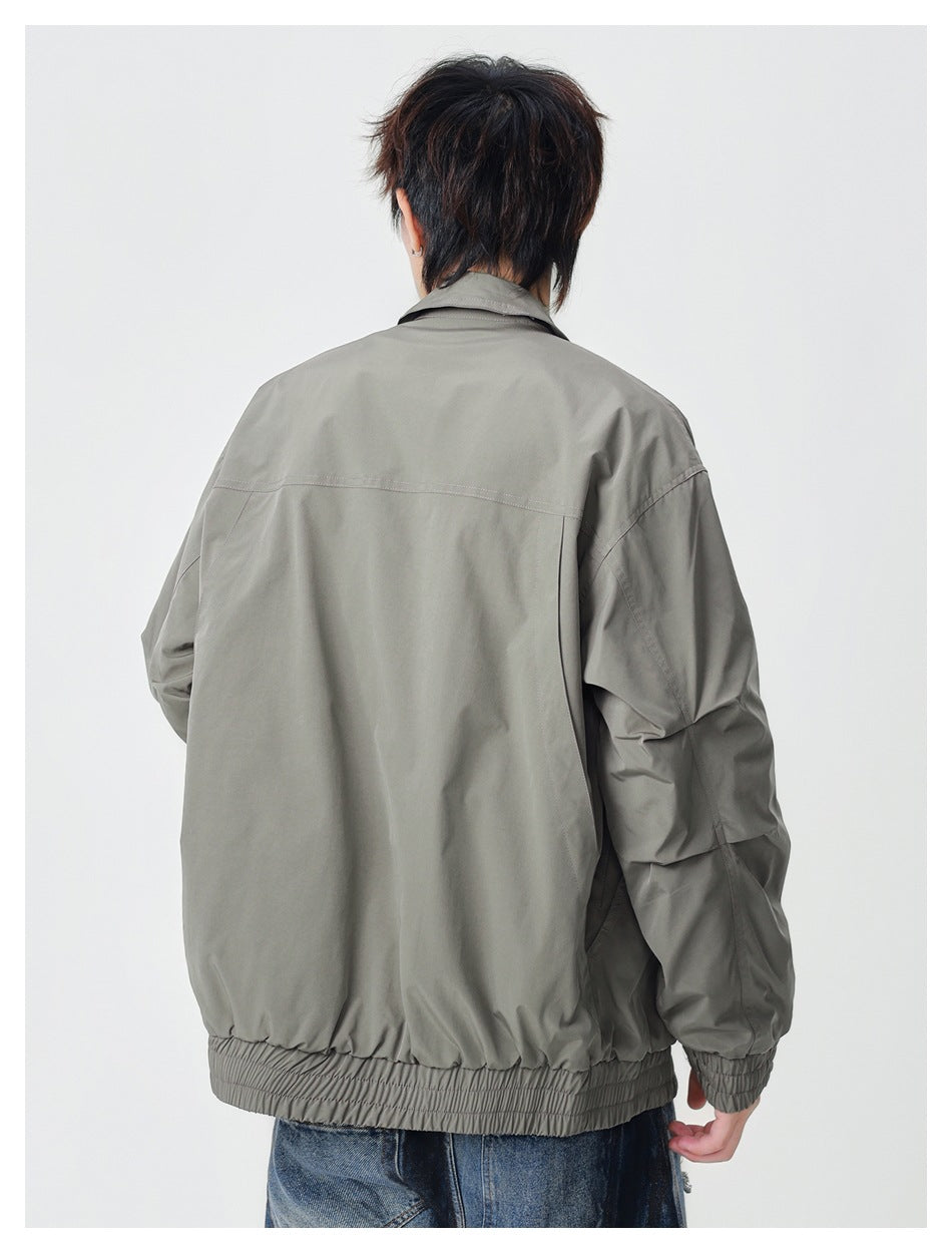 Rear view of a model wearing a gray-green jacket with a back yoke seam and elastic hem and cuffs.