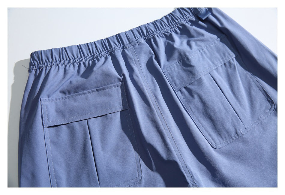 Close-up of blue cargo trousers showing the elastic waistband and two large flap pockets.
