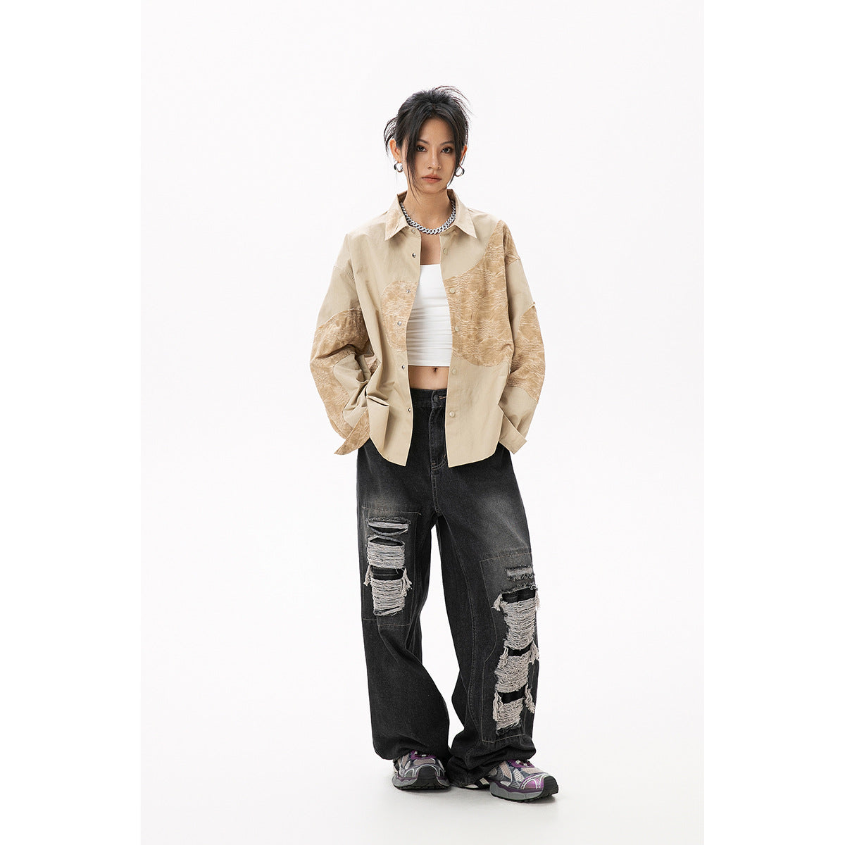 Model wearing a beige oversized button-up shirt with tan textured panels and wide black distressed jeans.