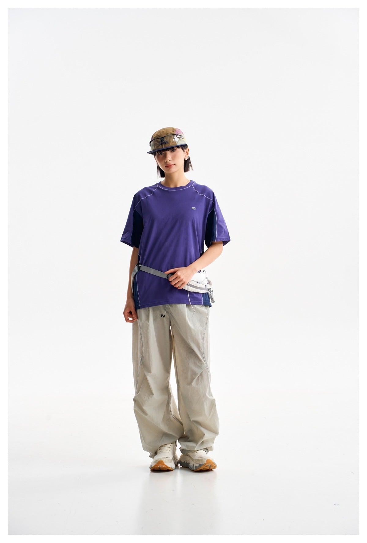 Model wearing a purple short-sleeve T-shirt with dark side panels and light contrast stitching.