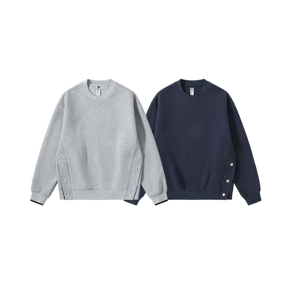 Front views of crewneck sweatshirts in heather gray and navy, with long sleeves, ribbed trims, and snap-fastened side panels.