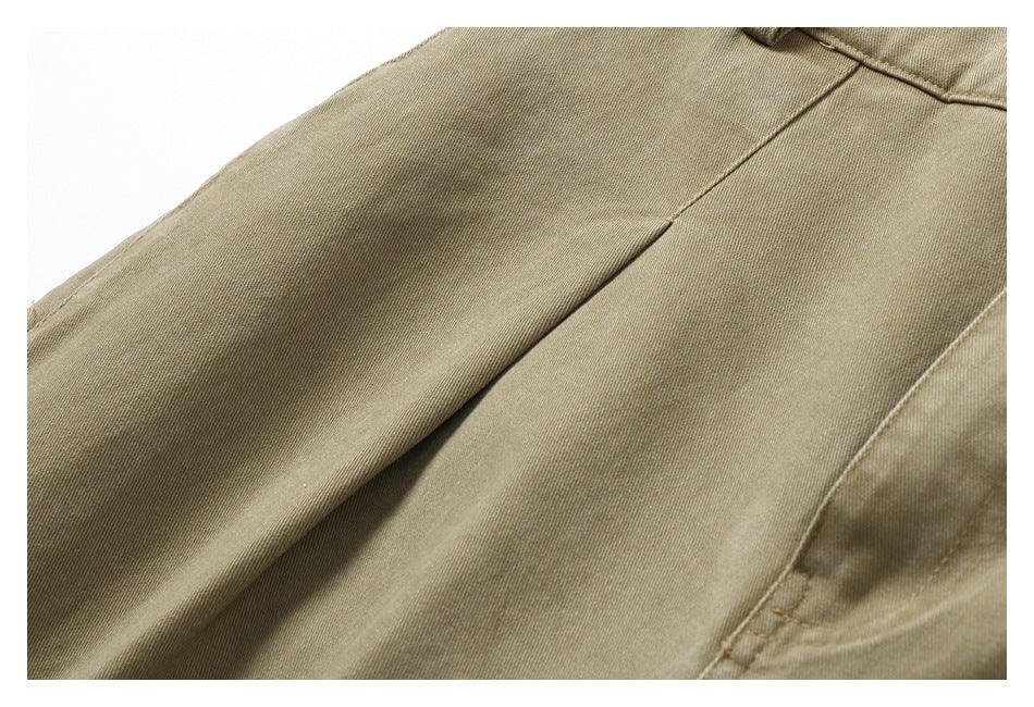 Close-up of khaki trousers showing diagonal seams and the fine woven surface.