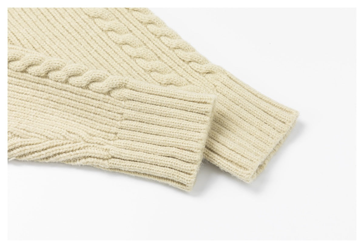 Close-up of the ivory cable-knit sleeve and its broad ribbed cuff.