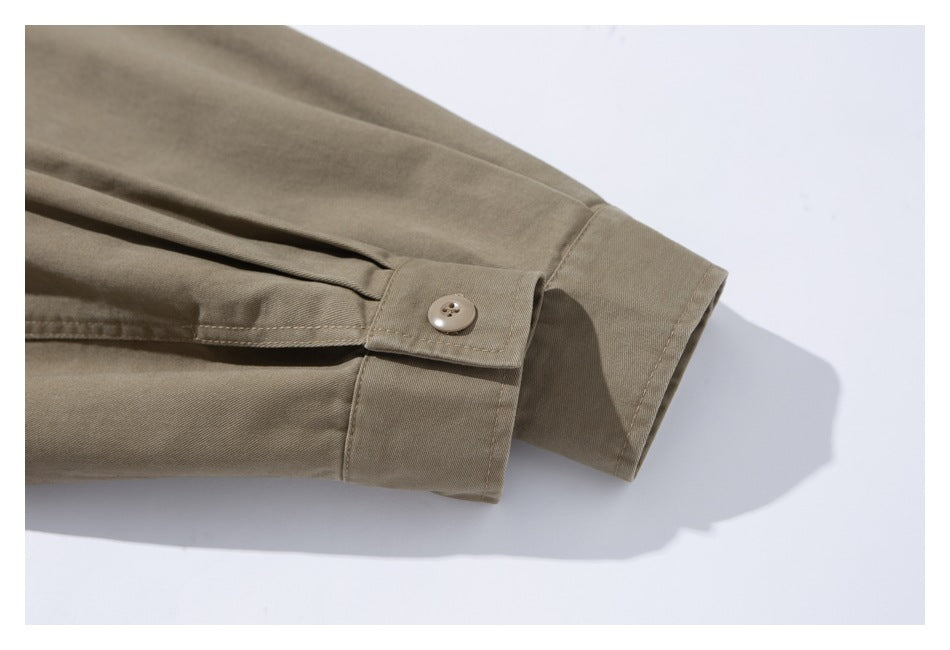 Close-up of a taupe jacket sleeve cuff with a buttoned tab and folded pleat.