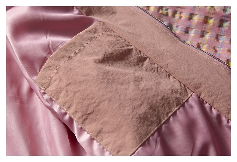 Close-up of the jacket’s smooth pink lining and inner seam beside the plaid outer fabric and zipper.