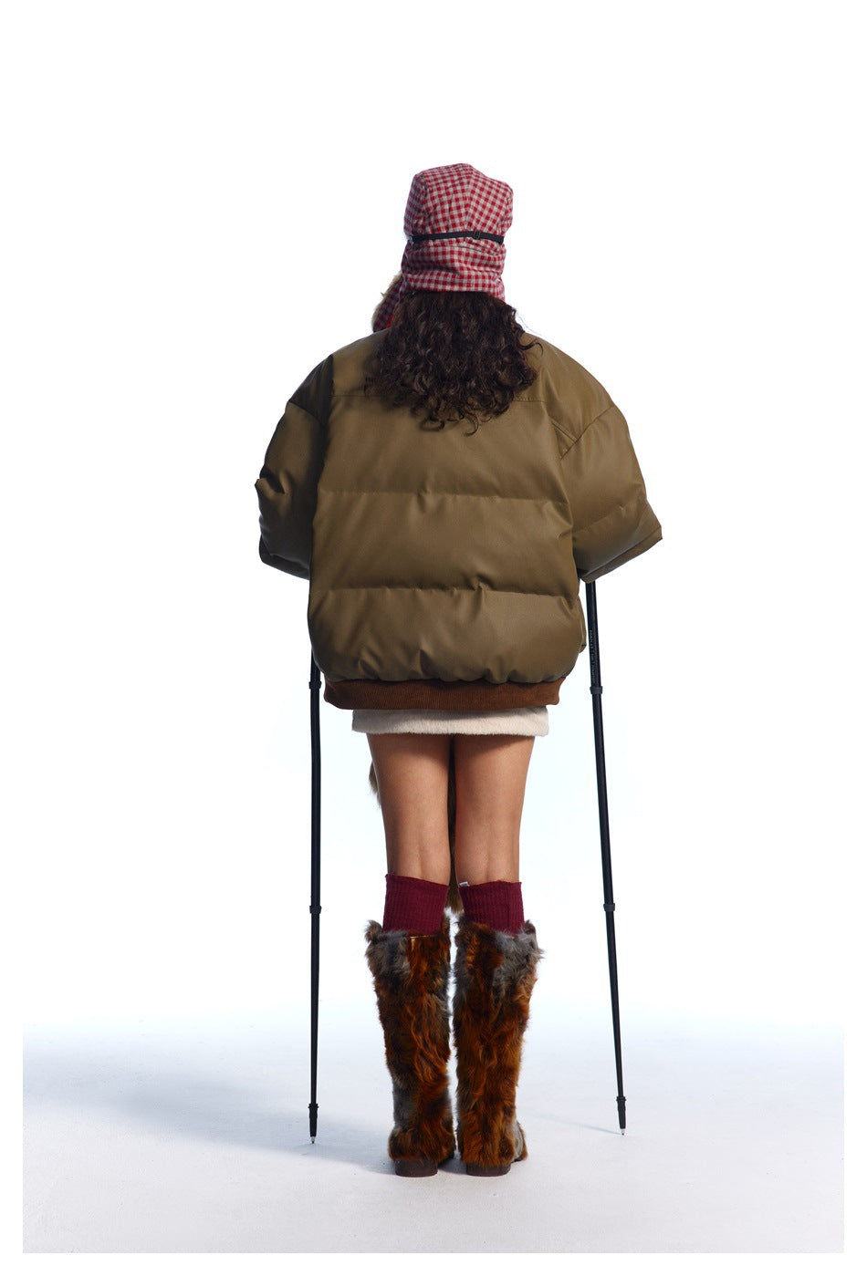 Back view of a model wearing an olive-brown puffer jacket with a ribbed hem.