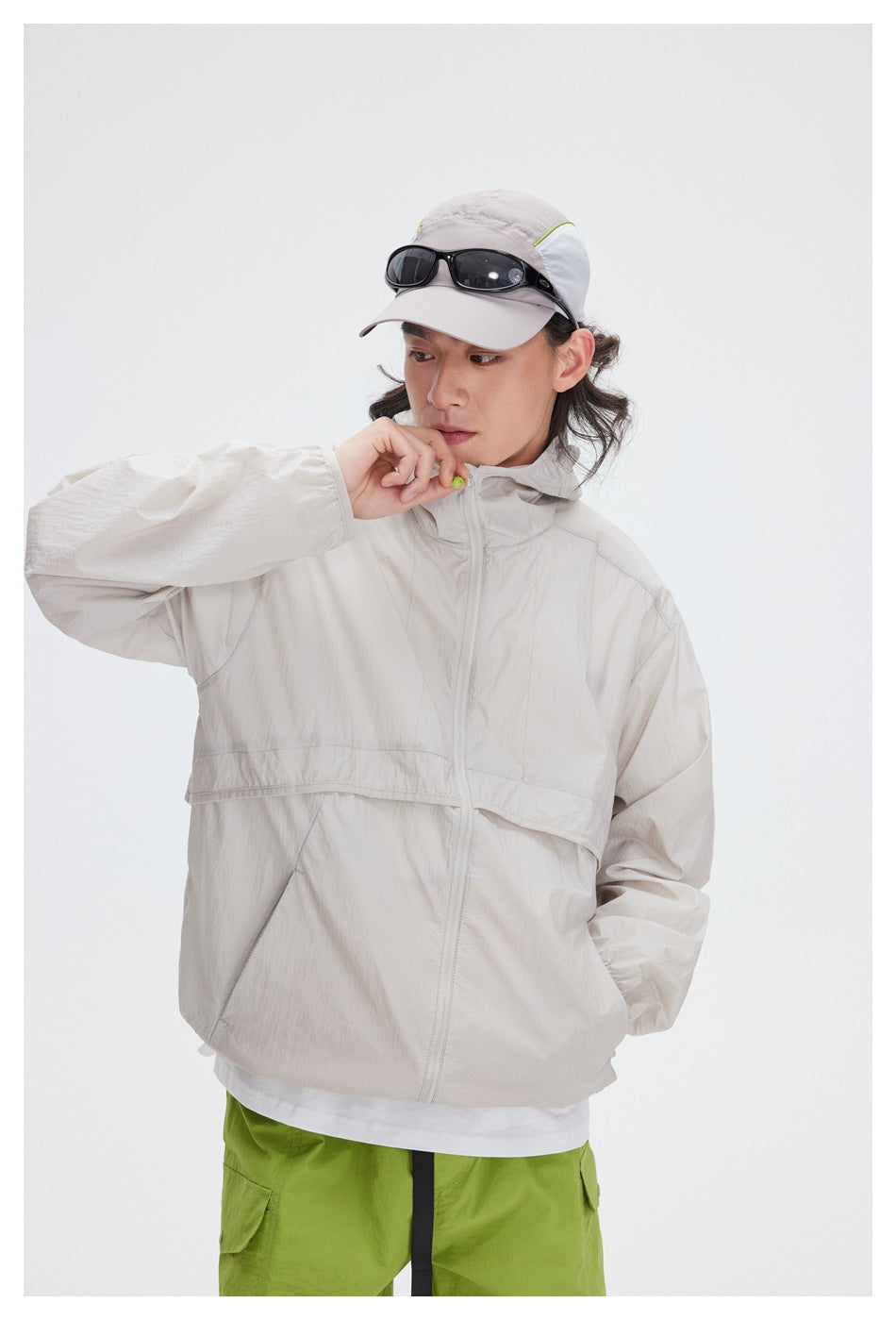 Close view of a model wearing a light beige hooded zip jacket, showing its front seams and collar.