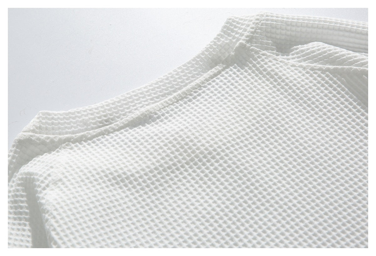 Close-up of a white waffle-textured garment with its neckline and overlapping front edge visible.