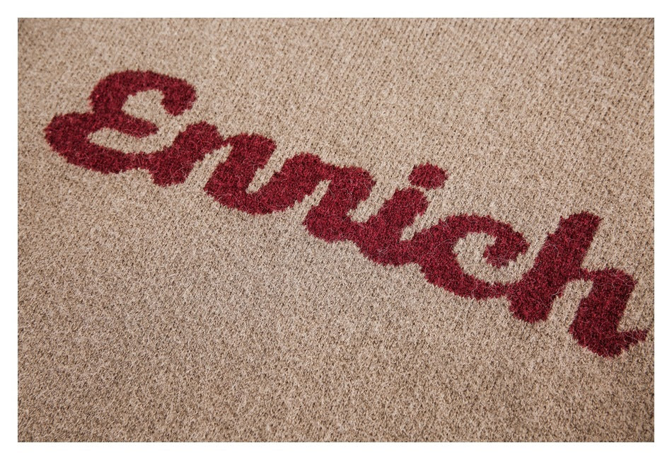 Close-up of burgundy script lettering across the textured taupe sweater knit.