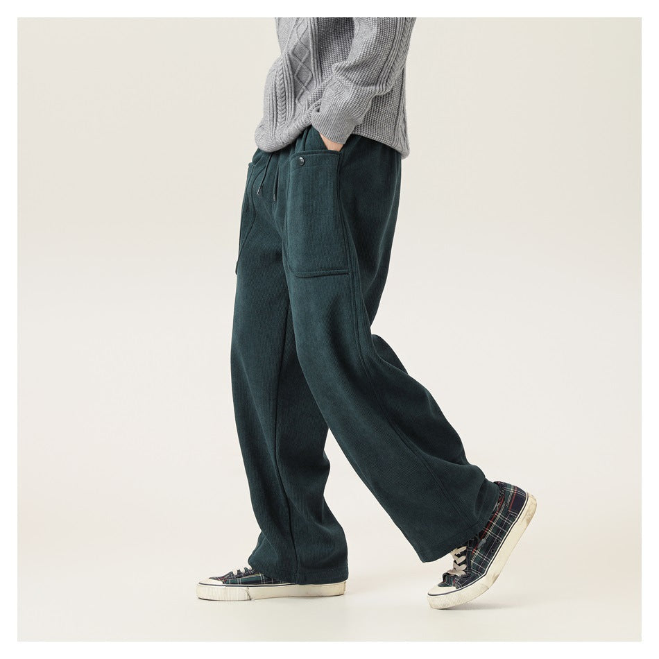 Side view of a model wearing dark teal wide-leg pants with a large patch pocket and drawstring waist.