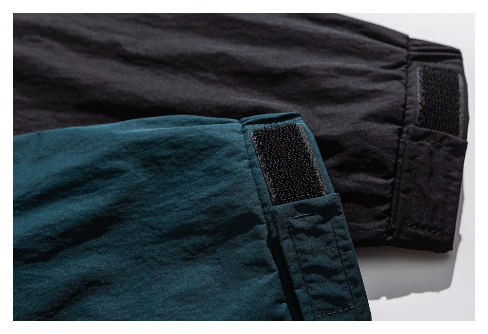 Close-up of black and deep teal jacket sleeves with adjustable hook-and-loop cuffs.