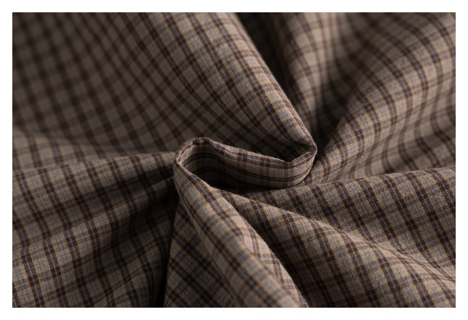 Close-up of brown and gray plaid fabric gathered to show its check pattern and texture.