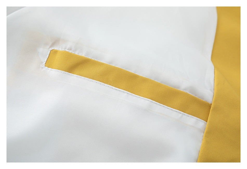 Close-up of a white garment with a mustard-yellow inset pocket trim.