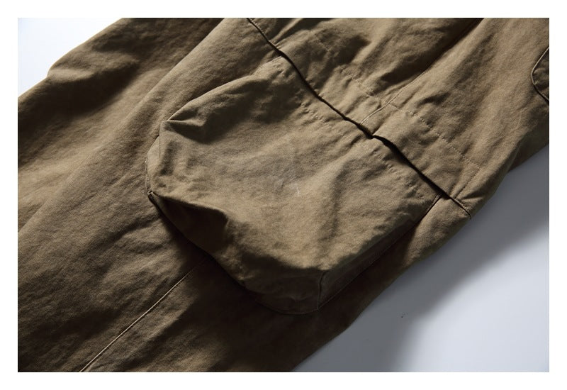 Close-up of a large rounded patch pocket on olive-brown bottoms.