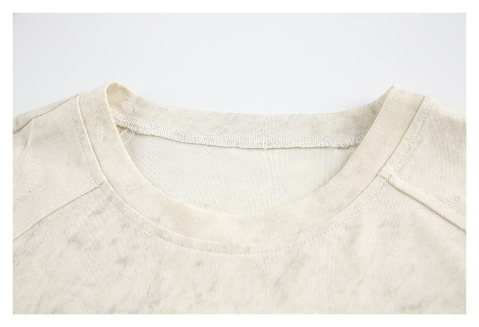 Close-up of the crew neckline, stitching, and raglan seams on an ivory T-shirt.